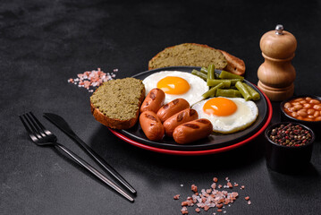 Tasty English breakfast of fried eggs, beans, asparagus, sausages with spices and herbs