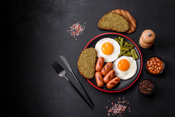 Tasty English breakfast of fried eggs, beans, asparagus, sausages with spices and herbs