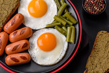 Tasty English breakfast of fried eggs, beans, asparagus, sausages with spices and herbs