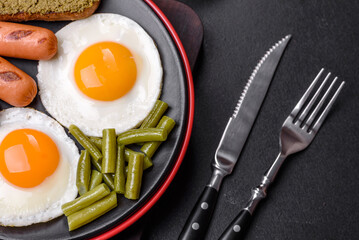 Tasty English breakfast of fried eggs, beans, asparagus, sausages with spices and herbs