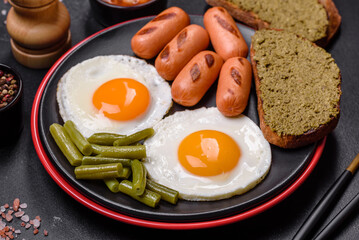 Tasty English breakfast of fried eggs, beans, asparagus, sausages with spices and herbs