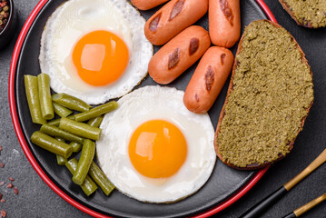 Tasty English breakfast of fried eggs, beans, asparagus, sausages with spices and herbs