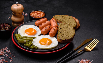 Tasty English breakfast of fried eggs, beans, asparagus, sausages with spices and herbs