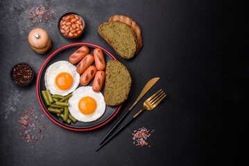 Tasty English breakfast of fried eggs, beans, asparagus, sausages with spices and herbs
