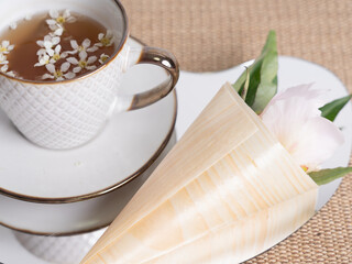Artistic still life. A cup of tea with small white flowers. Pink peony flower in a horn. Flowers for design.