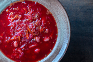 Ukrainian national dish red borsch in a ceramic plate on a wooden background. Beetroot soup is a national dish in Ukraine, top view, copy space for text