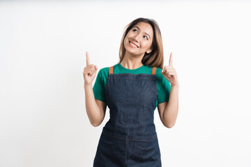 Young asian woman dressed in barista uniform pointing finger to the side on white background.