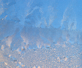 snow frost in the form of natural patterns on the window pane against the background of the morning sky