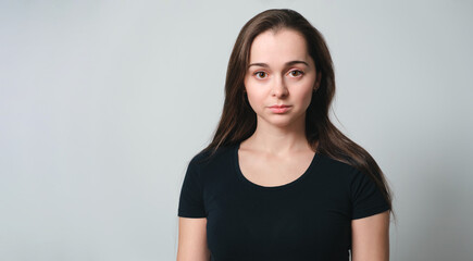 Portrait of cute beautiful young 30 years woman isolated on grey background close-up. Copy space. Banner. Pretty face. Looking at camera. White skin, big eyes and long brown hair. European appearance