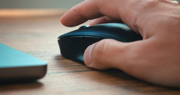 Click black computer mouse on a work desk. Working with a PC or laptop at workplace, close-up