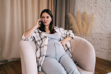 Young childbearing woman talking on mobile phone in living room