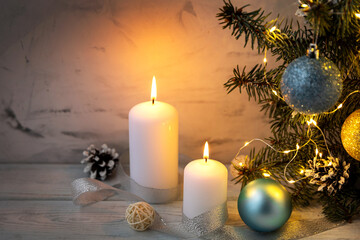 Christmas composition on the table with white candles and fir branches with a glowing garland. New Year, holidays.