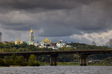 View of the big city on the hills over wide river in awesome bright sunset. View at Kyiv-Pechersk Lavra National Reservend and Paton bridge. Kyiv. Ukraine.