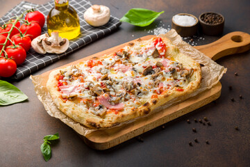 Roman pizza with ham and mushrooms on Roman dough, pinsa on dark brown table