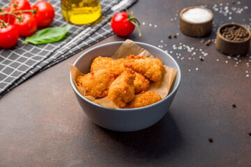 Fried chicken nuggets on bowl on dark brown table