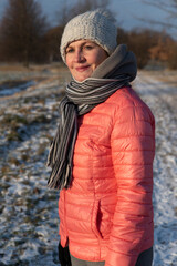 An adult attractive woman in warm clothes walks in a winter park