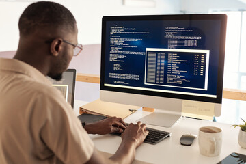 Fototapeta na wymiar Black developer in glasses debugging software when working on computer in office