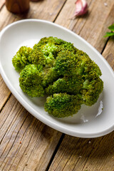 Broccoli in a white plate on wooden table vertical