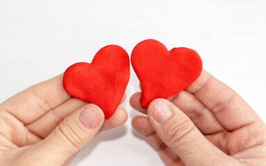 Fototapeta premium plasticine clay red color heart shape in kid woman mother son hands palm.diy do it yourself activities valentines love february 14th day back to school creative.modeling clay imagination development