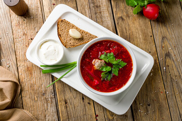 Borscht with sour cream top view on wooden table