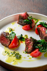 Beef steak sliced with spinach on plate on dark stone table macro close up vertical