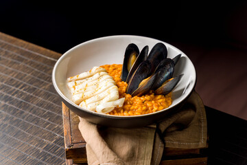 risotto with seafood on wooden table, squid and mussels