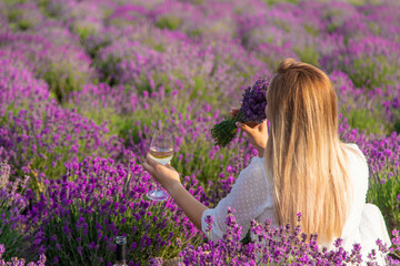the girl holds a glass of wine on the background of a lavender field. Selective focus.