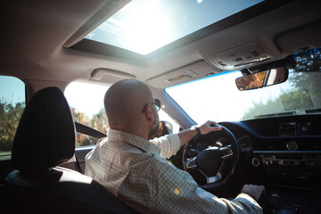 brutal bald bearded middle-aged man drives a car