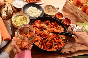 People are picking up cooked kimchi into glass jars.