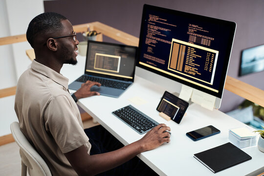 Cheerful Black software developer examining code written by coworkers