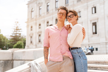 Young beautiful hipster couple in sunglasses in love walking on old city street