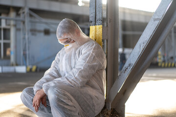 Despair healthcare worker in white covid protective overalls. Tired Male caucasian doctor in depression during coronavirus pandemic