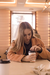 beautiful young woman with a glass of takeaway coffee sits in a cafe
