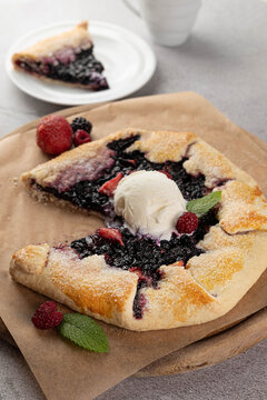 Blurred image of a galette with berries and a scoop of vanilla ice cream. The concept of simple homemade food.