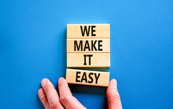 We make it easy symbol. Concept words We make it easy on wooden cubes. Beautiful blue table blue background. Businessman hand. Business motivational we make it easy concept. Copy space.