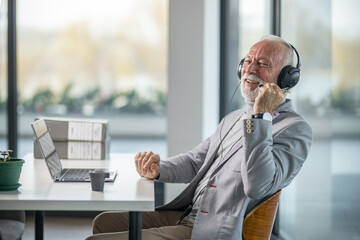 Senior business man sitting in his office and talking online meeting