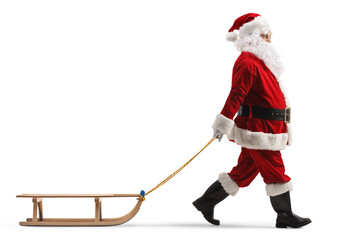 Full length profile shot of santa claus pulling a wooden sleigh - obrazy, fototapety, plakaty