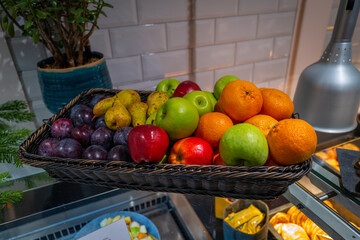 on a breakfast buffet there is a bowl with different kinds of fruits