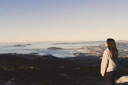 Rear view of a woman standing on a mountain looking at view of Cies Islands, Baiona and Nigran, Val Minor, Pontevedra, Galicia, Spain