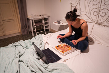 Young Asian woman having pizza while watching movie