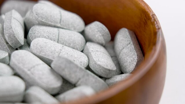 Tryptophan sedative pills in wooden rustic container. Remedy for depression and insomnia. Natural pharmaceutical antidepressant. Rotation