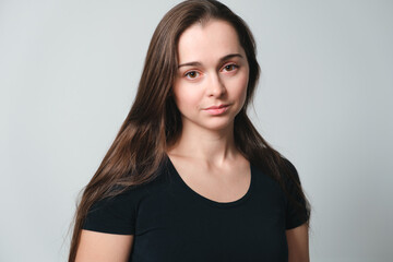 Portrait of cute beautiful young 30 years woman isolated on grey background close-up. Copy space. Banner. Pretty face. Looking at camera. White skin, big eyes and long brown hair. European appearance
