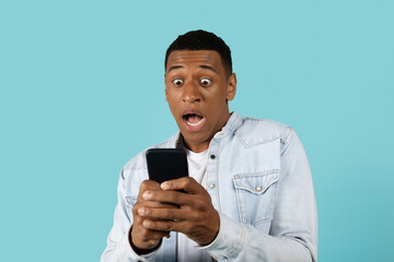 Scared shocked funny young african american guy in casual with open mouth scream, look, at phone
