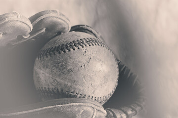 Old vintage style baseball in glove closeup for sports background.