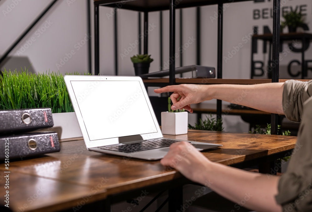 Poster finger pointing, showing at blank screen mockup, template of laptop computer in modern office interi