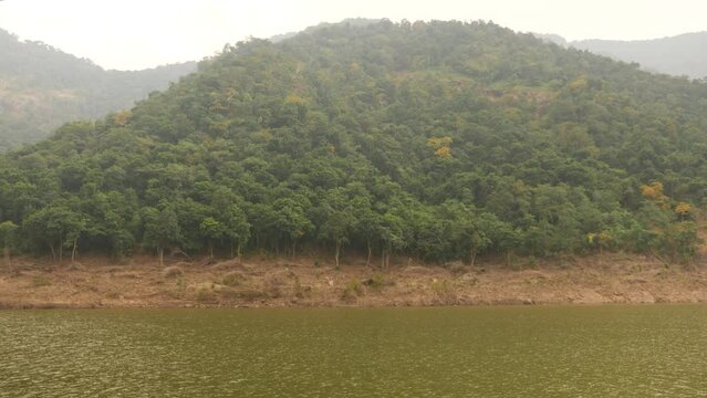 Rear View short clip of a bushy hill shore and green sea, sky and mountain background