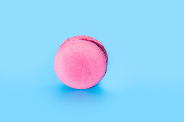 Pink french macaroon or macaron on blue background. Tasty colourful macarons.