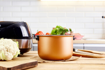 Modern pot of multicooker and products on kitchen table. Capacity for multi cooker at home.