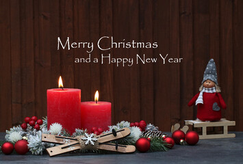 Christmas card: Red burning candles and Christmas decorations against a wooden background with the text Merry Christmas and a Happy New Year.