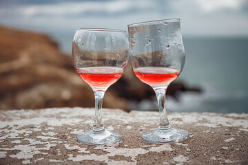Two glasses of pink champagne on the handicap of the mountains and the sea. Travel and romance. Beautiful landscape. recreation and alcoholic beverages.